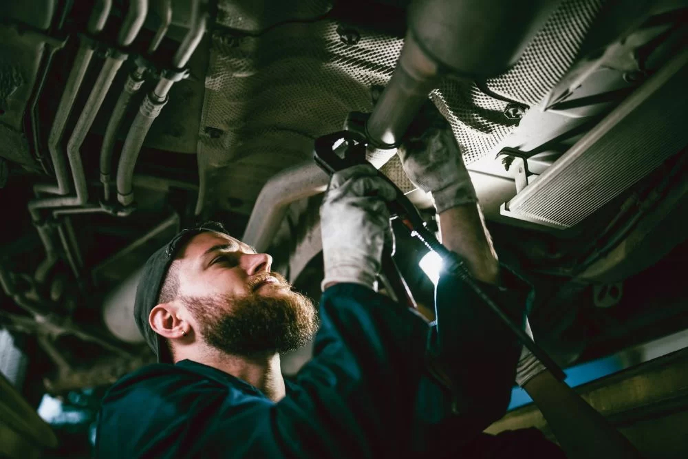 mechanic working on exhaust system repair under a vehicle